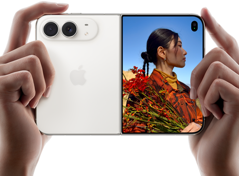 iPhone Duo, Star White colour, held by two hands in horizontal orientation, unfolded, left panel shows 48MP Dual Fusion rear cameras, right panel shows person getting their picture taken on outer display, the subject of the photo is able to see their face as their picture is getting taken using Duo Preview