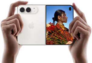 iPhone&nbsp;Duo, Star White colour, held by two hands in horizontal orientation, unfolded, left panel shows 48MP Dual Fusion rear cameras, right panel shows person getting their picture taken on outer display, the subject of the photo is able to see their face as their picture is getting taken using Duo Preview